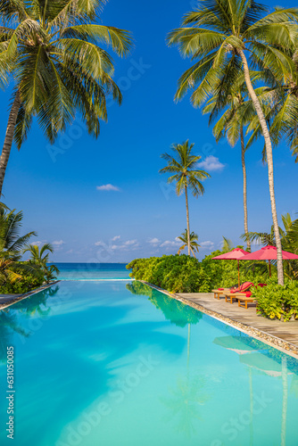Fototapeta Naklejka Na Ścianę i Meble -  Leisure travel landscape, infinity swimming pool blue sky. Tropical resort hotel in Maldives. Fantastic relax and peaceful vibes, chairs loungers under umbrellas and palm  tree leaves. Luxury vacation