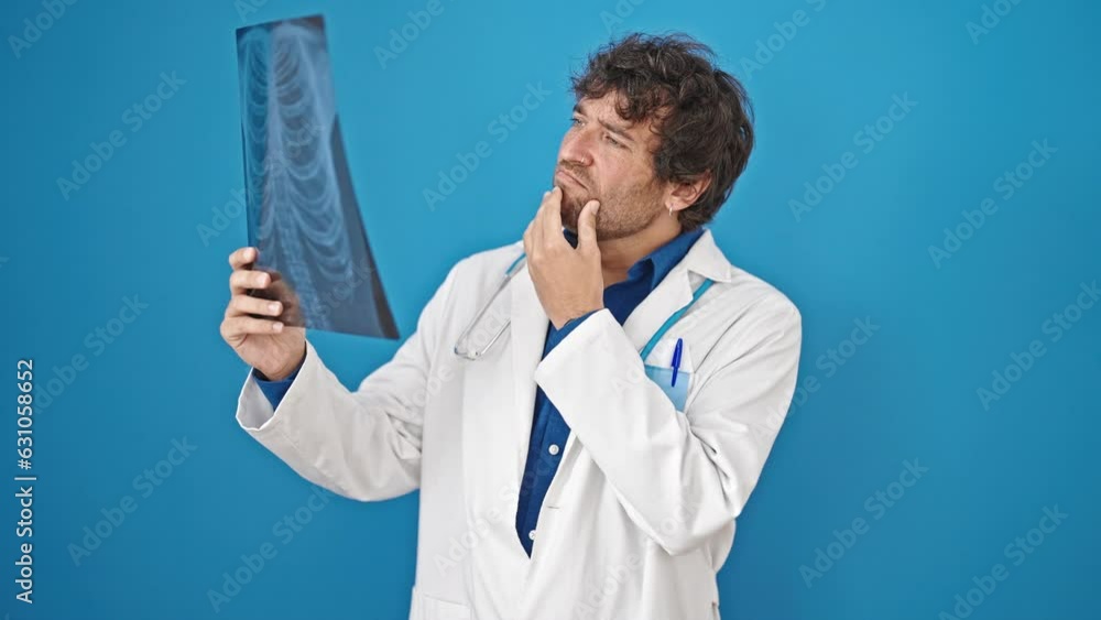 Young hispanic man doctor looking xray over isolated blue background Young hispanic man doctor looking xray over isolated blue background