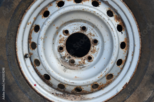 Old silver wheel rim with bolt hole and car tire close up