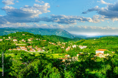 travel summer view from hill to a nice european town with amazing buildings, green hills and mountains with amazing cloudy evening sky on background