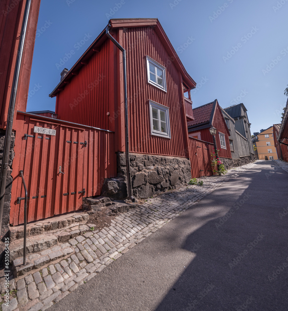 Slop with old wood red 1700s houses, red paling, black stone foundation, a sunny summer day in Stockholm Slop with old wood red 1700s houses, red paling, black stone foundation, a sunny summer day in Stockholm