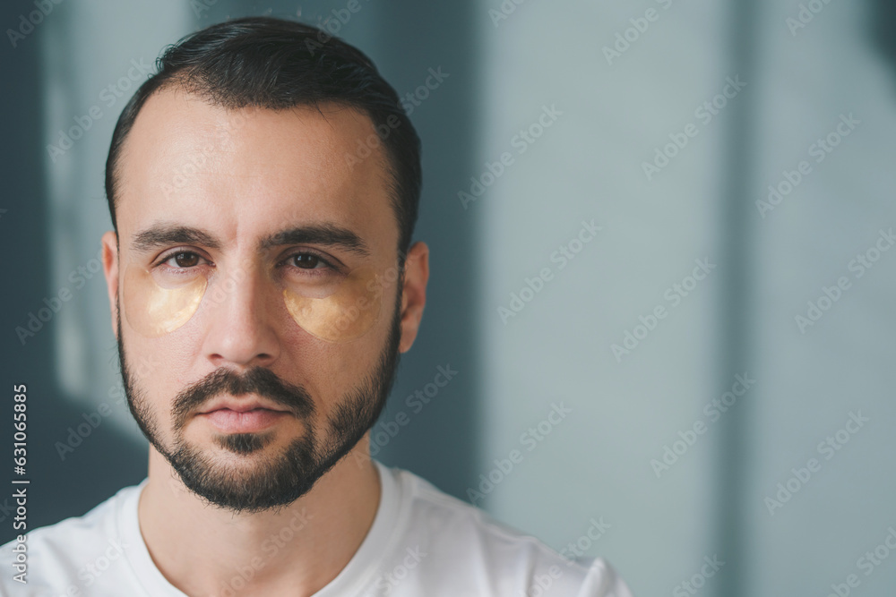 Close-up portrait of an attractive bearded man wearing eye facial patches modern uplift rejuvenation effect isolated background Close-up portrait of an attractive bearded man wearing eye facial patches modern uplift rejuvenation effect isolated background