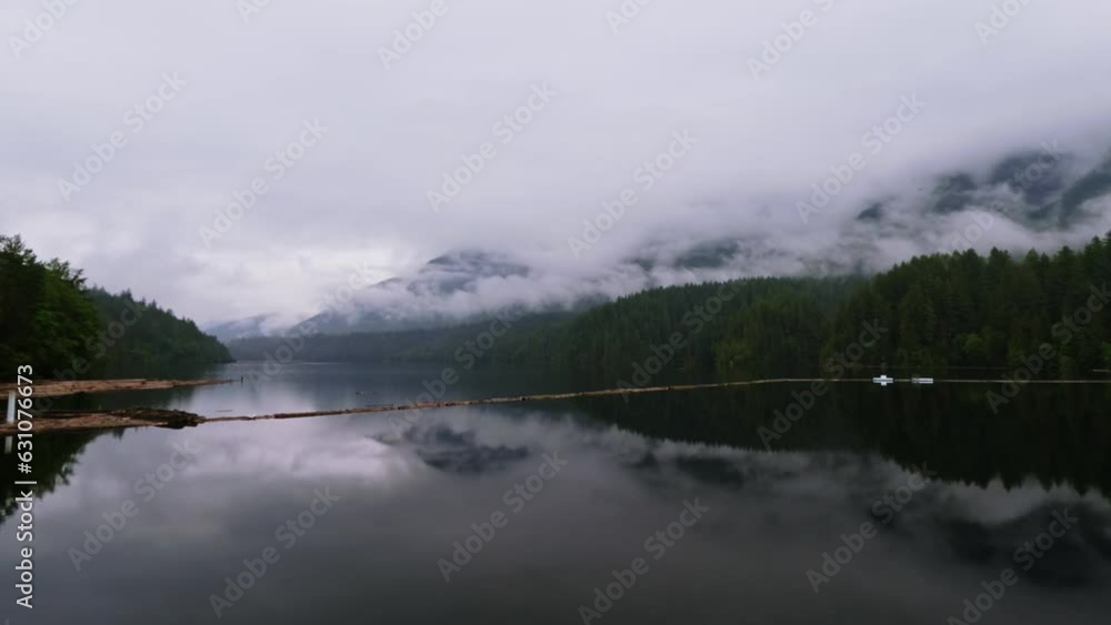 A Serene Lake With Forest Mountains and Heavy Fog Reflecting of the Water Surface In Vancouver, BC Canada. Ultra Wide Panning A Serene Lake With Forest Mountains and Heavy Fog Reflecting of the Water Surface In Vancouver, BC Canada. Ultra Wide Panning
