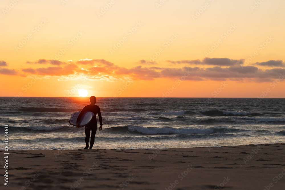 Silhouette of a man in wetsuit walking forward at bright sunset Silhouette of a man in wetsuit walking forward at bright sunset
