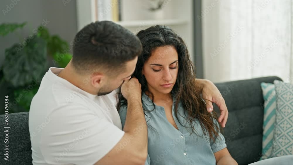 Man and woman couple sitting on sofa consoling girlfriend at home Man and woman couple sitting on sofa consoling girlfriend at home