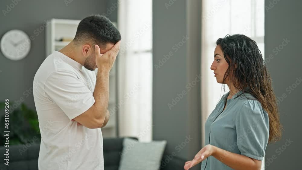 Man and woman couple standing together arguing at home Man and woman couple standing together arguing at home