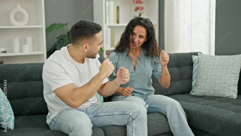 Man and woman couple singing song using remote control as a microphone at home Man and woman couple singing song using remote control as a microphone at home