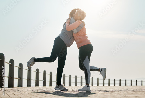 Running, hug and women by sea and ocean with love and care for fitness and exercise. Athlete, wellness and female friends on a beach promenade with motivation, embrace and smile from runner target photo