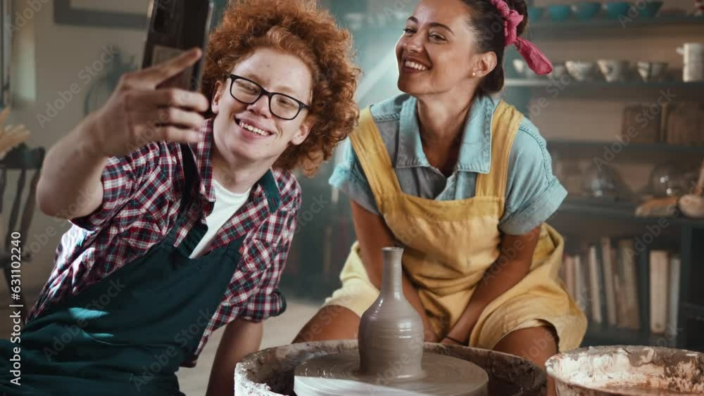 Clay students in the pottery workshop take a selfie using their phone