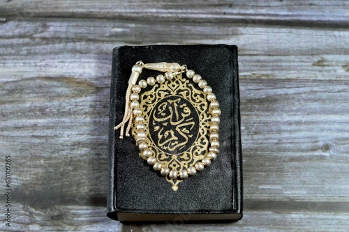 The holy Quran, Qur'an or Koran (the recitation) is the central religious text of Islam, a revelation from God (Allah) with an Islamic silver rosary that Muslims use it to give praise to Allah photo