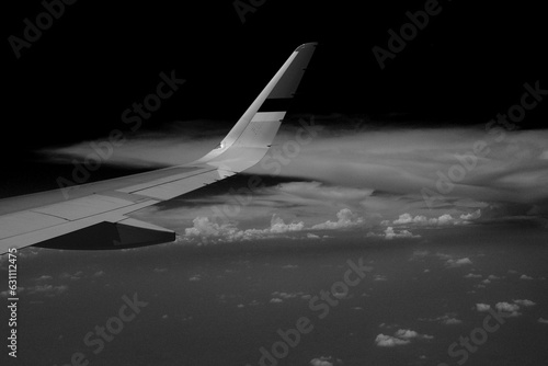 Black and white photo of a plane above the cloud