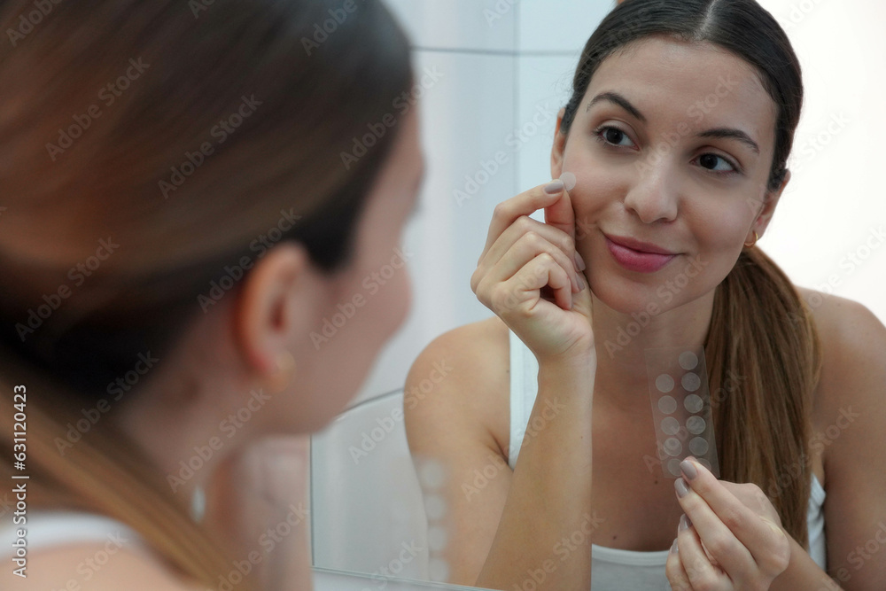 Close-up of pretty woman applying acne treatment anti-pickel patch on a pimple on her face at home Close-up of pretty woman applying acne treatment anti-pickel patch on a pimple on her face at home