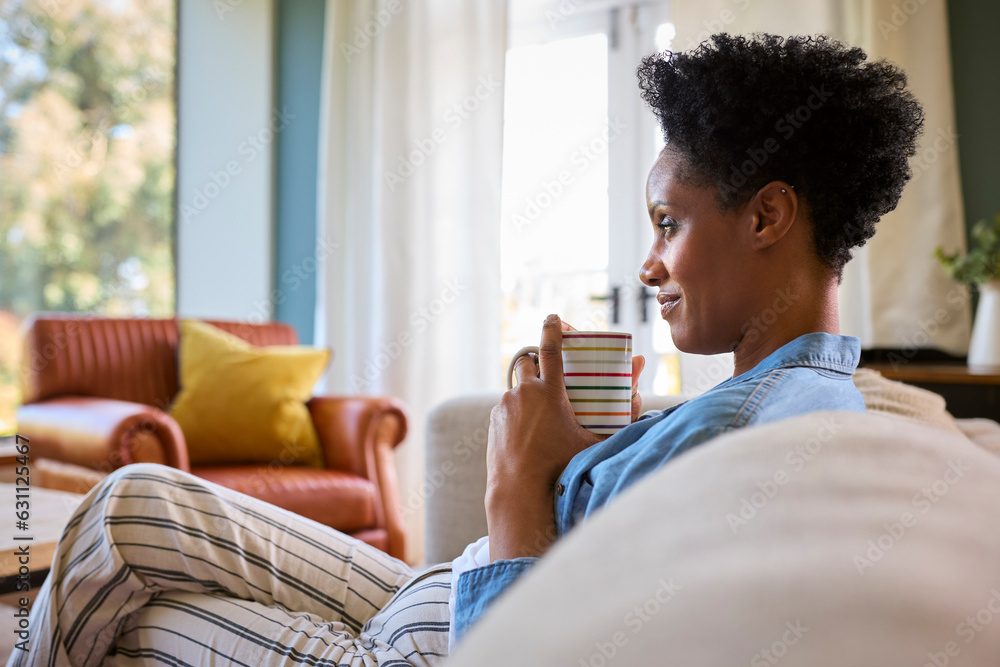 Mature Woman At Home Drinking Coffee Relaxing On Sofa In Lounge Mature Woman At Home Drinking Coffee Relaxing On Sofa In Lounge