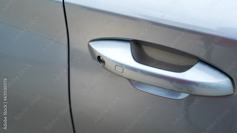 Close-up at door handle with keyless button of the luxury car in metallic grey color. Transportation equipment object, selective focus. 
