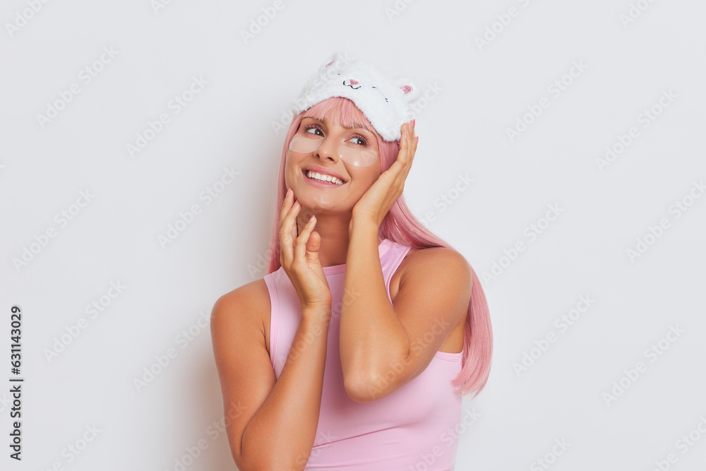 Close-up shot of pretty woman with long pink hair and sleep mask on her head posing on white background with smile, copy space, healthy woman concept Close-up shot of pretty woman with long pink hair and sleep mask on her head posing on white background with smile, copy space, healthy woman concept