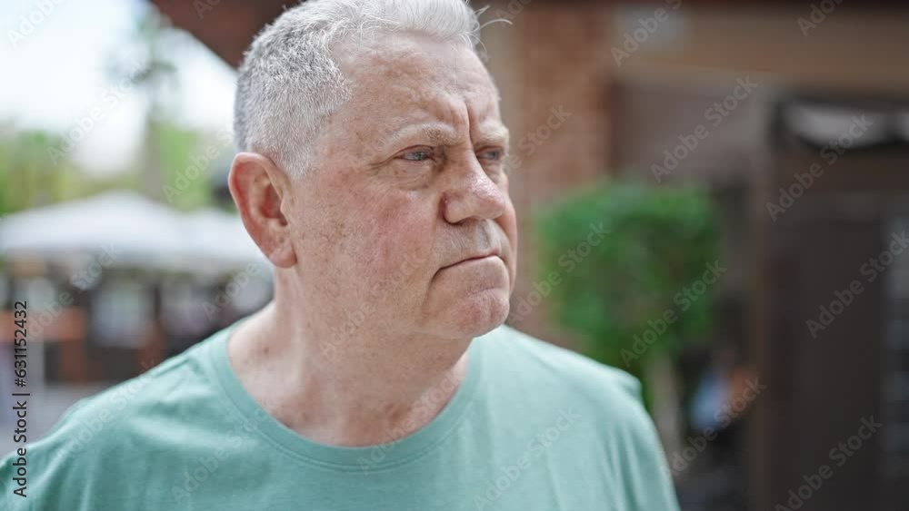 Middle age grey-haired man standing with serious expression at street Middle age grey-haired man standing with serious expression at street