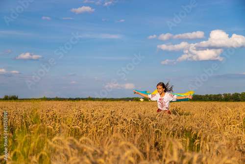 Child in a field of wheat with the flag of Ukraine. Selective focus.