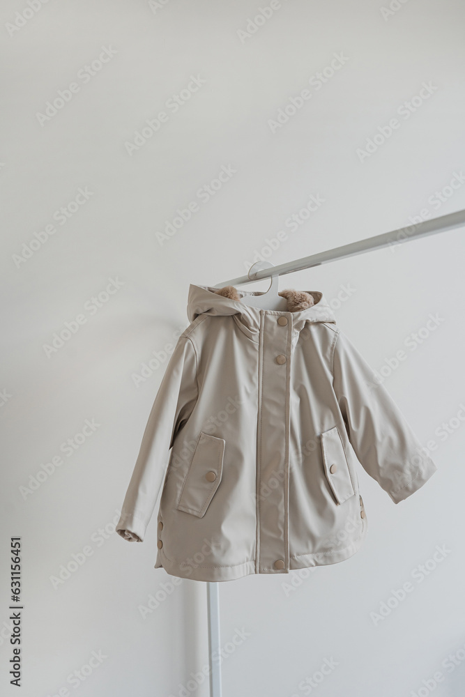 Baby's kids fashion. Neutral beige raincoat on hanger over white background. Children's fashion Baby's kids fashion. Neutral beige raincoat on hanger over white background. Children's fashion