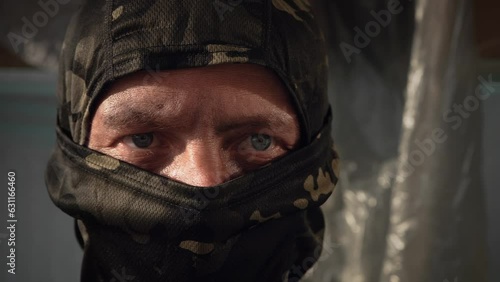 Man puts on a military balaclava. The concept of preparing for military action or fraud, robbery. Close-up. A man in a khaki fabric mask.