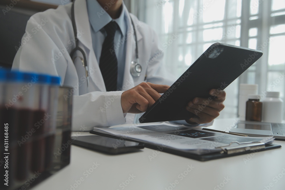 Confident doctor man holding a pill bottle and writing while talking with senior patient and reviewing his medication at office room. Confident doctor man holding a pill bottle and writing while talking with senior patient and reviewing his medication at office room.