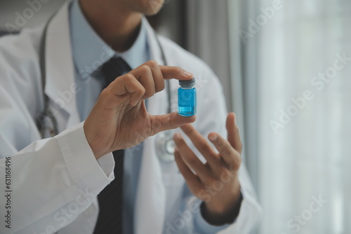 Confident doctor man holding a pill bottle and writing while talking with senior patient and reviewing his medication at office room.
