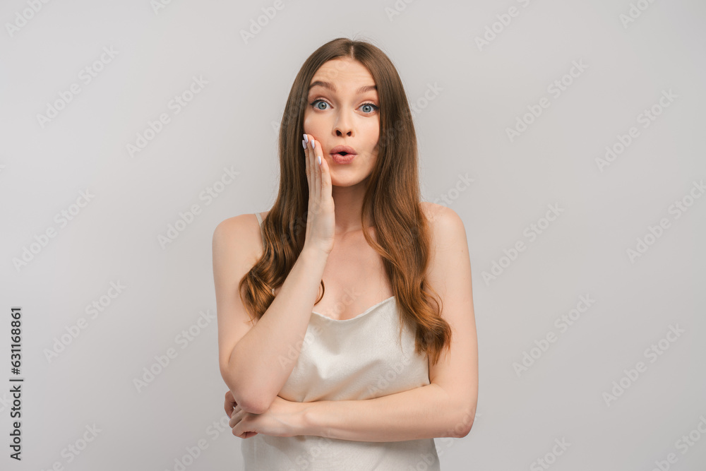 Excited woman in dress feeling surprised holding hand on face, looking at camera Excited woman in dress feeling surprised holding hand on face, looking at camera