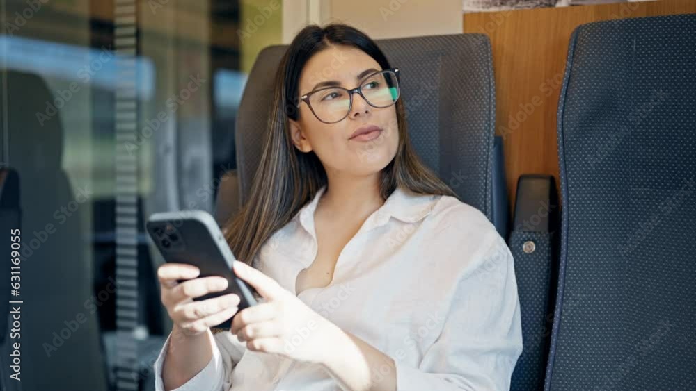 Young beautiful hispanic woman using smartphone sitting at train station Young beautiful hispanic woman using smartphone sitting at train station