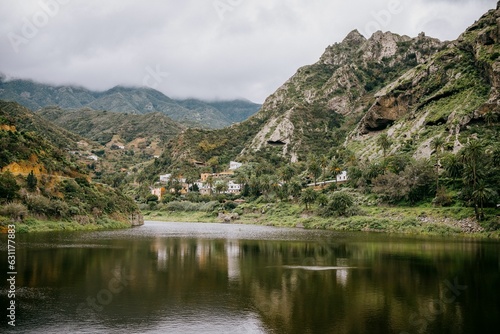 Tranquil lake surrounded by rolling mountains, with clouds descending in the distance,La Gomera