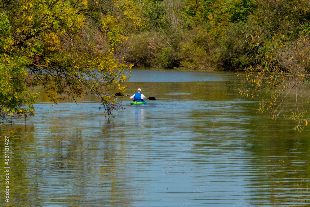 Kayaker Paddling On The River With Fall Colors In The Trees Kayaker Paddling On The River With Fall Colors In The Trees