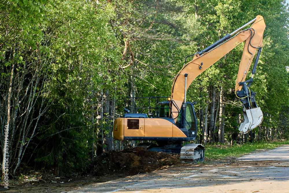 Crawler excavator deepens storm ditch on country road. Crawler excavator deepens storm ditch on country road.