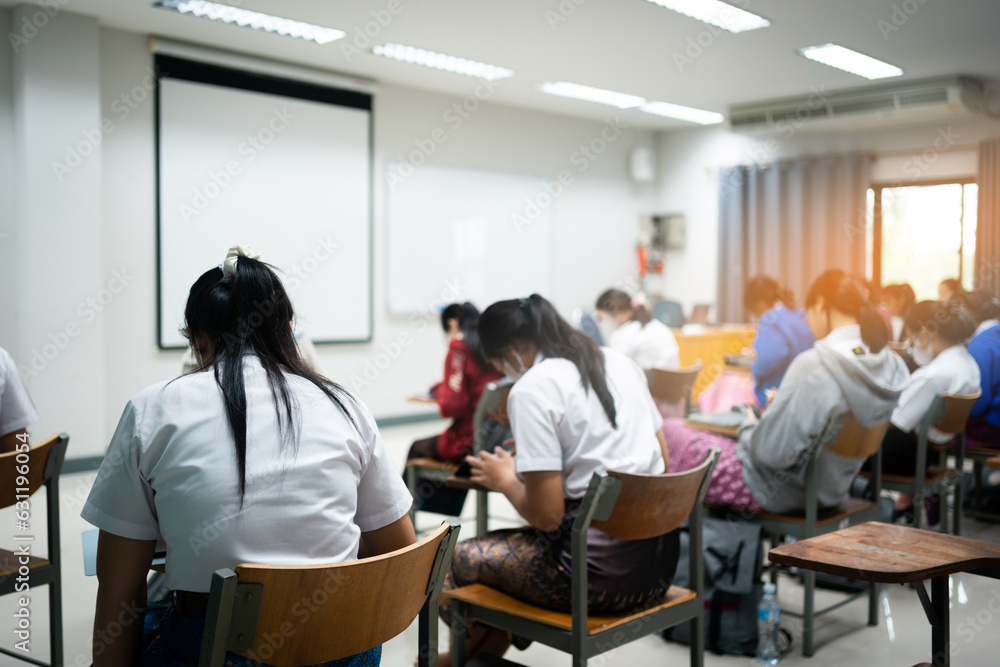 Rear view of college students doing examination in the classroom