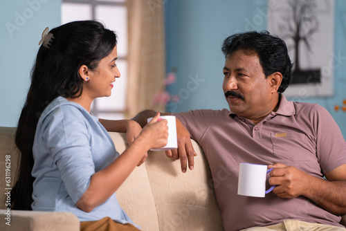 Happy indian daughter with father spending time talking while having tea together at home - concept of leisure time,Joyful Conversation and Companionship