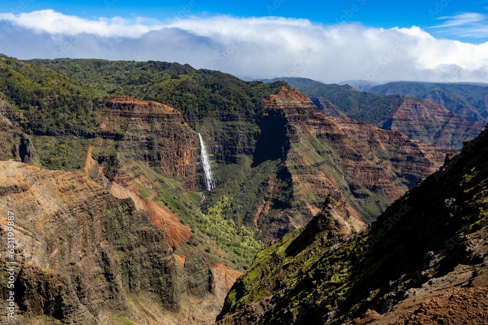 Aerial view of a waterfall in green mountains in Waimea Canyon State Park in Kauai County, Hawaii