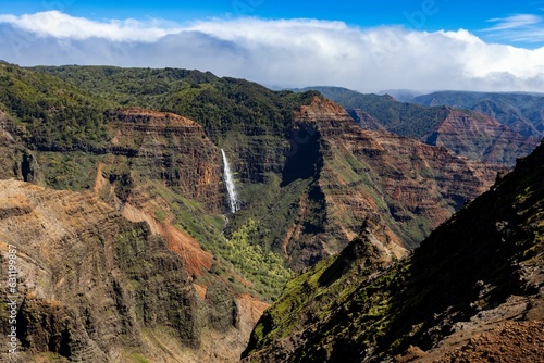Aerial view of a waterfall in green mountains in Waimea Canyon State Park in Kauai County, Hawaii