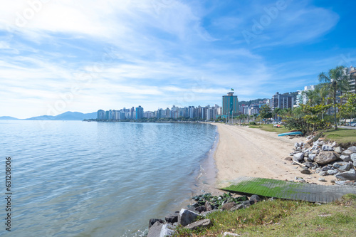 Beach with the silhouette of the city of floriano ́polis in santa catarina, landscape with sea, blue sky, stones and buildings photo