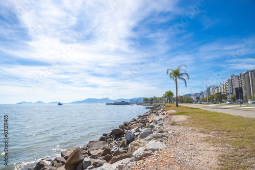 Beach with the silhouette of the city of floriano ́polis in santa catarina, landscape with sea, blue sky, stones and buildings photo