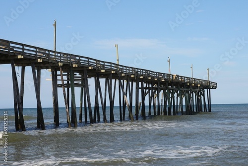 pier with wooden columns over the ocean and blue sky in the background © William75/Wirestock Creators
