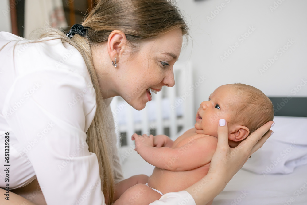 Young mother having fun with cute baby boy on bed, natural tones, love emotion