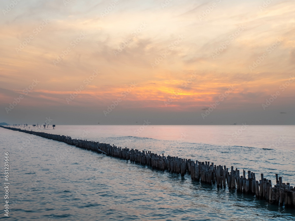 Sea view near mangrove forest with man made wooden barrier for wave protection, under morning twilight colorful sky in Bangkok, Thailand