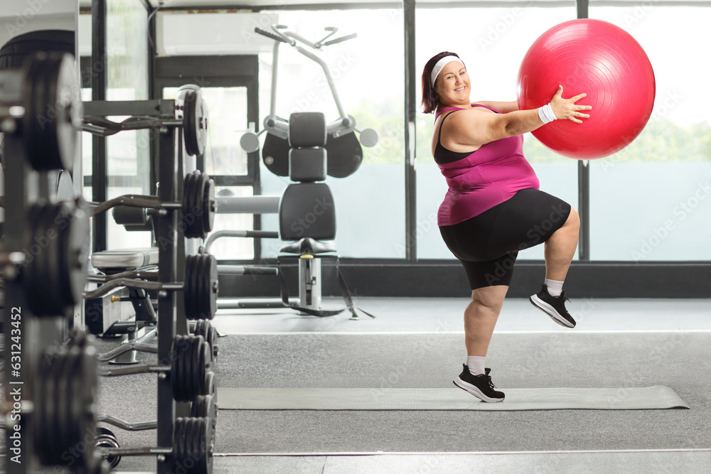 Fototapeta premium Cheerful overweight woman exercising with a fitness ball