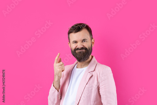 Bearded man dressed in a pink jacket with glasses. Emotional studio portrait.