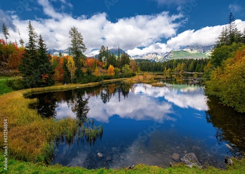 Fototapeta Naklejka Na Ścianę i Meble -  Beautiful mountain lake with a reflection of autum park on water and high peaks in the Background. The new Strbske pleso lake in High Tatras mountains in Slovakia.
