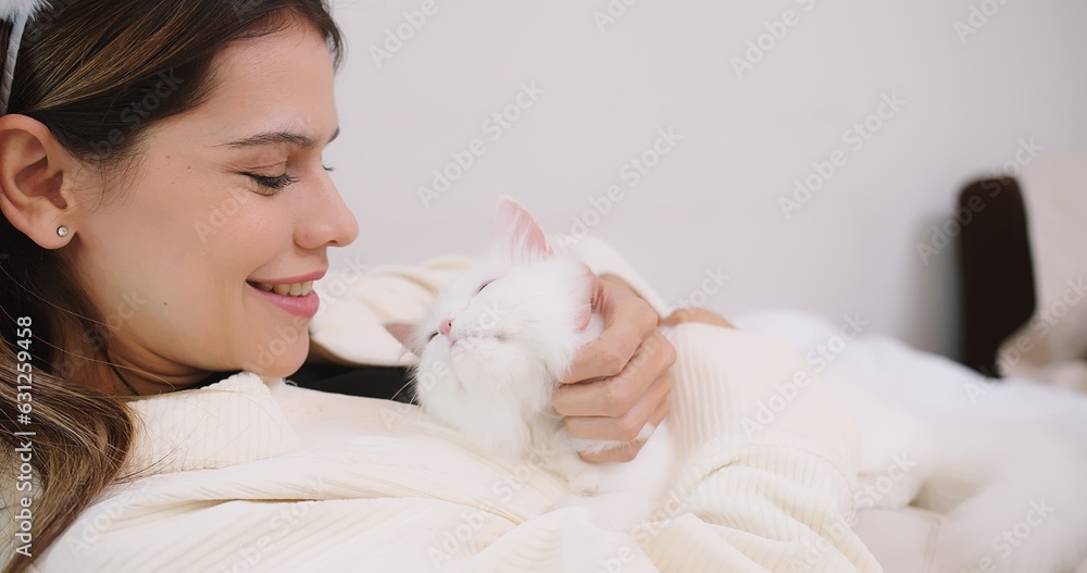 Attractive woman petting cute little fluffy white cat on sofa in living room, owner stroking domestic cat animals at home, Relationship between pets and people. Attractive woman petting cute little fluffy white cat on sofa in living room, owner stroking domestic cat animals at home, Relationship between pets and people.