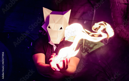 wolf costume with hands of fire. realistic effect of fire between the hands. creative lighting with costume. wolf papercraft. wolf head mask. man in the night with neon light and animal mask. 
