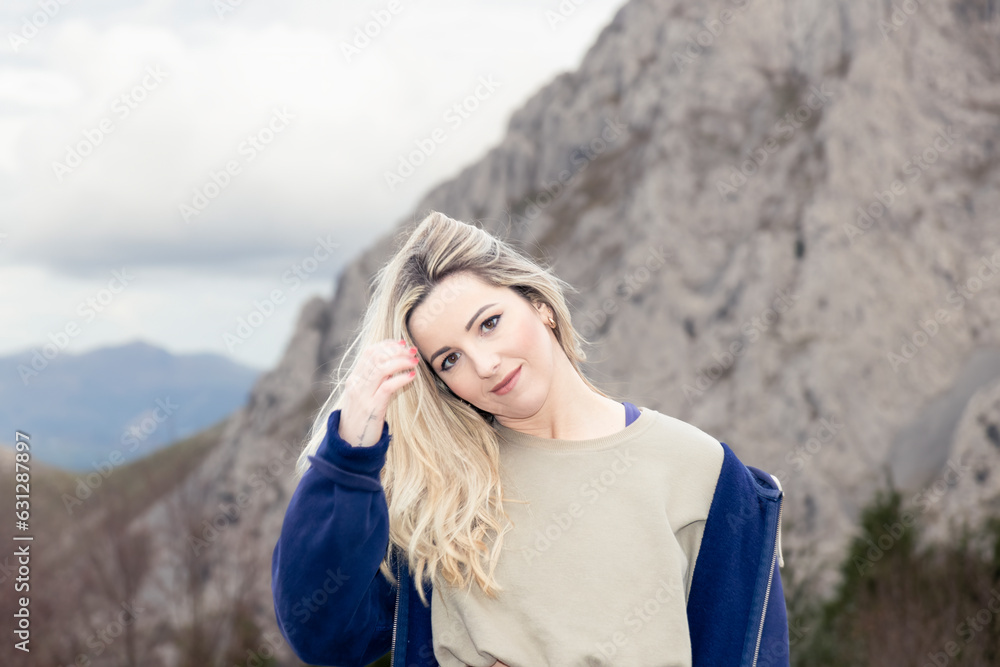 Blonde Serenity: Woman's Tranquil Touch with Wind-Swept Hair amidst Mountain Scenery Blonde Serenity: Woman's Tranquil Touch with Wind-Swept Hair amidst Mountain Scenery