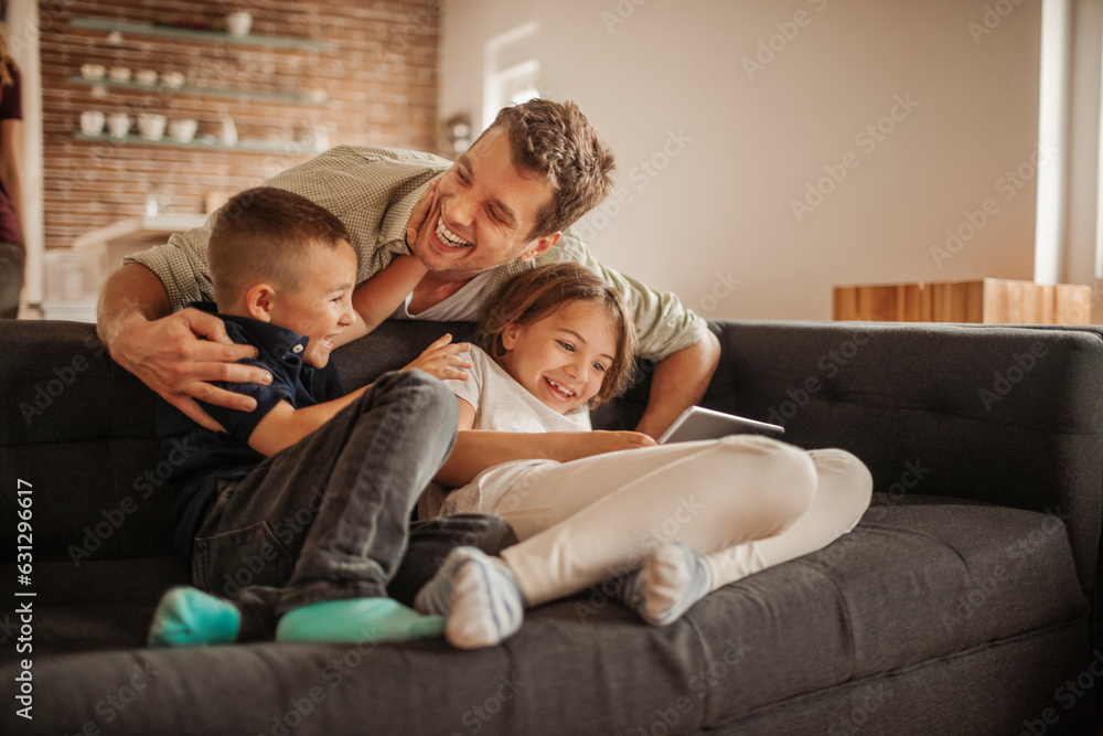 Single father playing with his kids on the couch in the living room at home