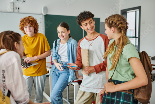 happy teenagers talking in classroom, back to school, classmates communicating during school break