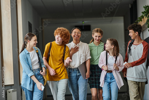 back to school, cultural diversity, teacher and teenage students walking in school hallway, smile © LIGHTFIELD STUDIOS