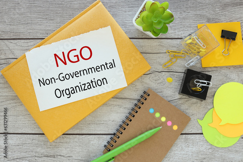 text on a torn page from a notepad on a yellow notepad.potted plants.words NGO nongovernmental organization photo
