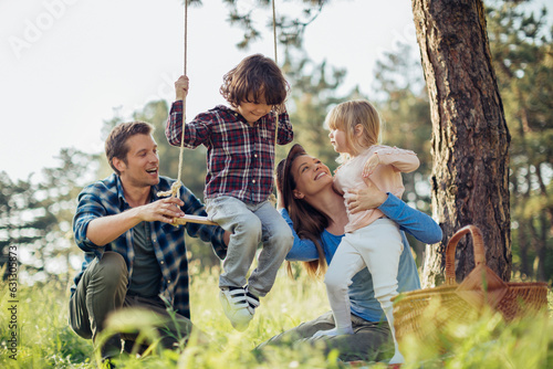 Young family having a picnic and using a swing in a park in nature